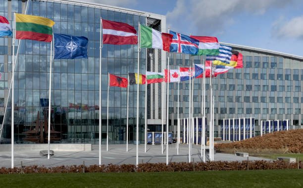 The Ultimate Guide to Conference Alerts: Stay Ahead in 2025 Exterior view of the glass-fronted NATO Headquarters building with numerous national flags flying in front. Often used for conference alerts and updates on diplomatic summits.